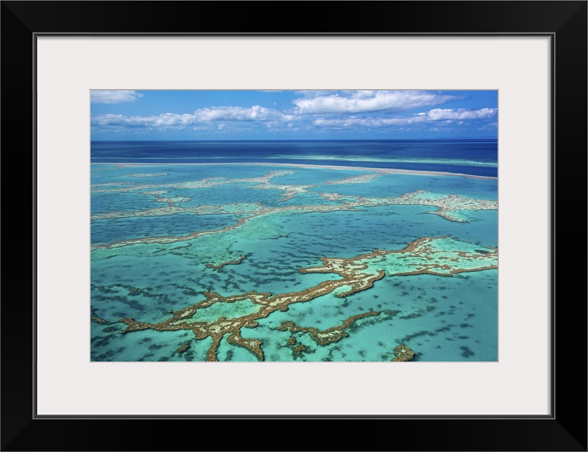 Aerial photo of Great barrier reef showing reef area with some blue water and slightly cloudy sky in background.