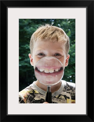 Boy behind magnifying glass smiling