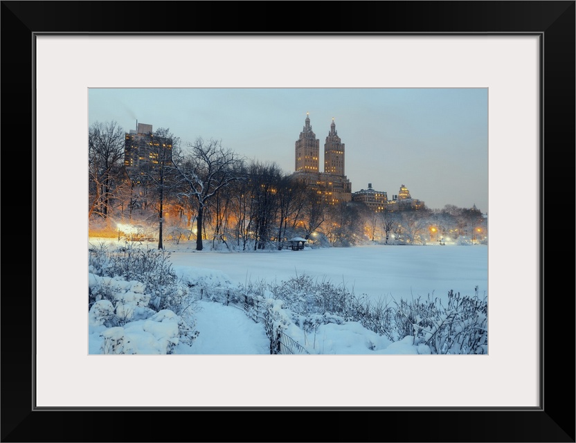 Central Park in winter at night with skyscrapers in midtown Manhattan, New York City.