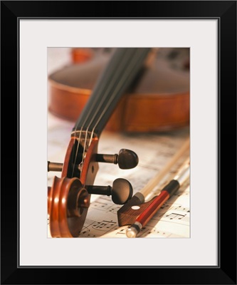 Close up of violin scroll and bow on sheet music