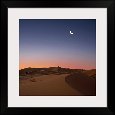 Crescent moon over dunes in Sahara Desert at dawn, Morocco.