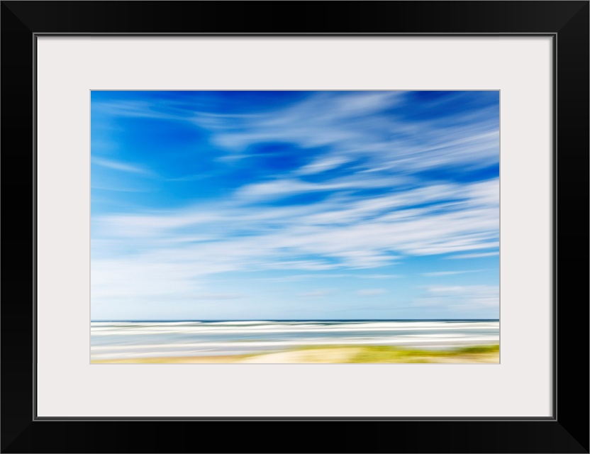 Intentional camera movement of ocean scene of with bright blue sky and wispy clouds. Teewah Beach, Queensland, Australia.