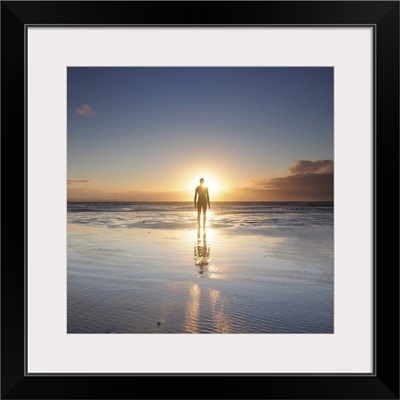 Man walking on beach at sunset, UK.