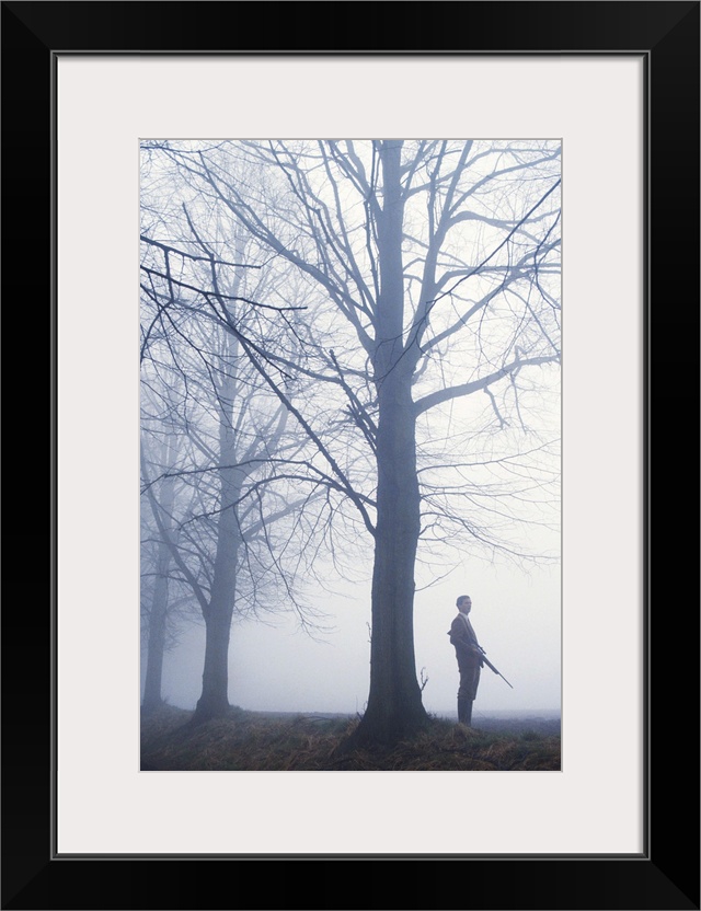 Man with rifle in forest, side view