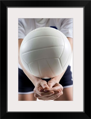 Mid section view of a young woman serving a volleyball