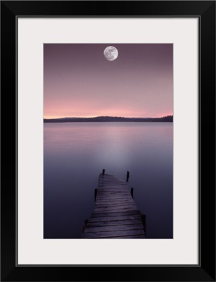 Moon over lake with pier at dusk