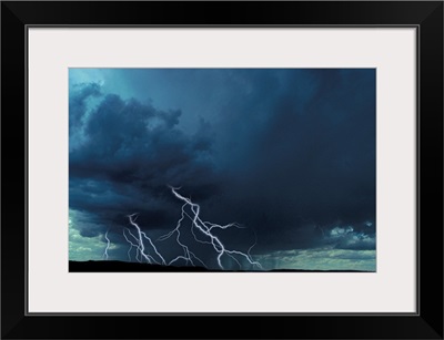 Multiple lightning bolts over rural landscape