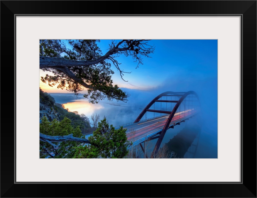 Large photograph displays an overpass on the Colorado River in Austin, Texas while a large mist flows over top of it.  Pho...