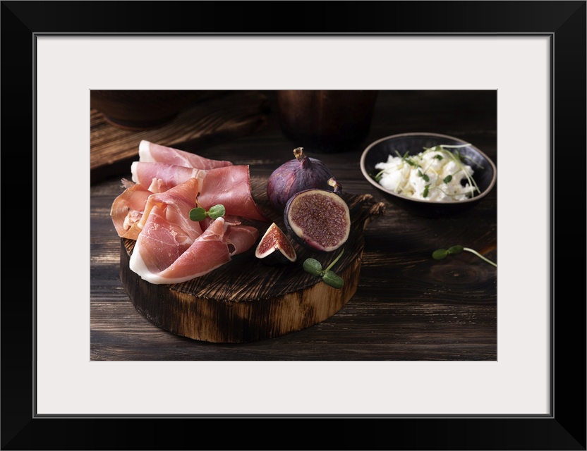 Prosciutto slices with figs on a dark wooden background, appetizer from dry cured ham. Rustic style. Ukraine.