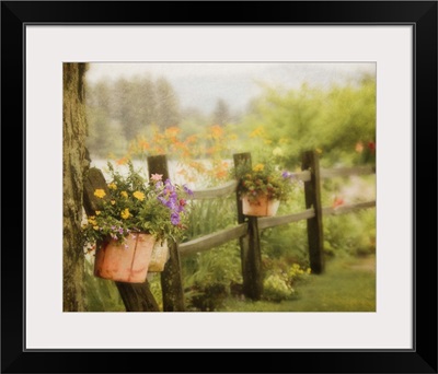 Rustic wooden fence with flowers in clay pots hanging on posts