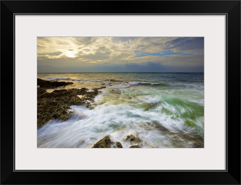 Rushing waves on coral reefs in Howan, Pingtung, after shower with setting sun shiny behind clouds.