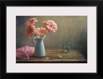 Still life with pink gerberas flowers in blue pitcher jug anf glass of water.