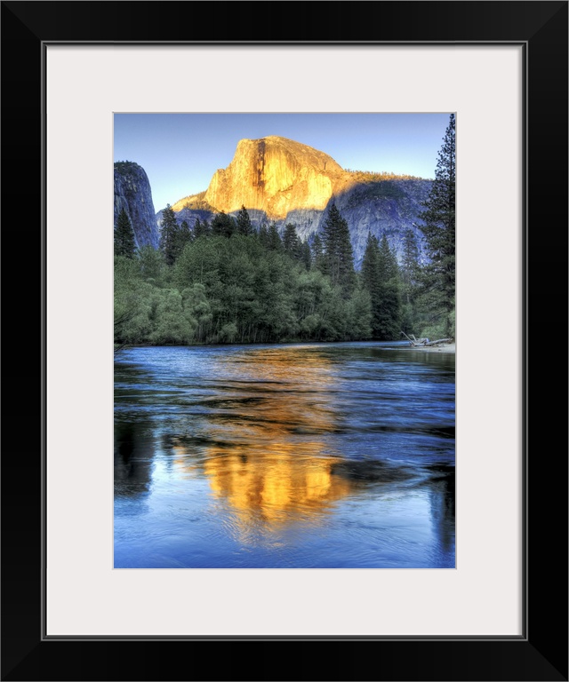 Golden light of sunset on half Dome reflecting in Merced river in Yosemite National Park.