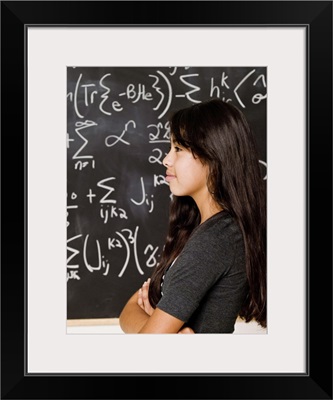 Teenage girl looking at blackboard with math equations