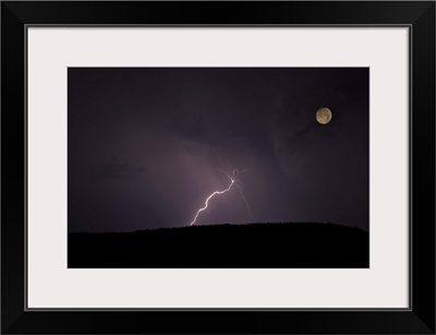 Thunderstorm, thunderbolt lightning, flash over mountain and moon at night.