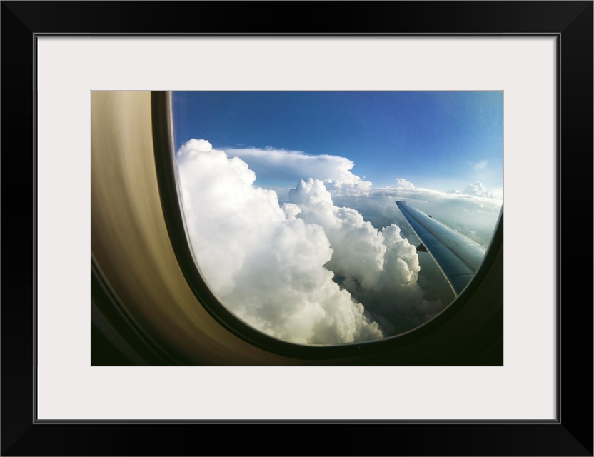 White fluffy clouds looking through airplane window.