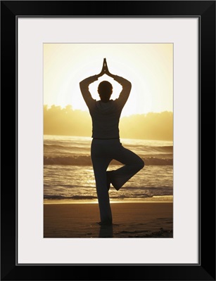 Woman doing yoga on beach at sunrise