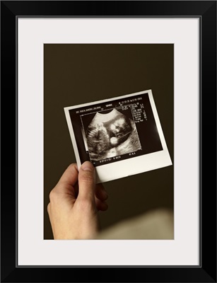 Woman holding ultrasonograph photo of baby