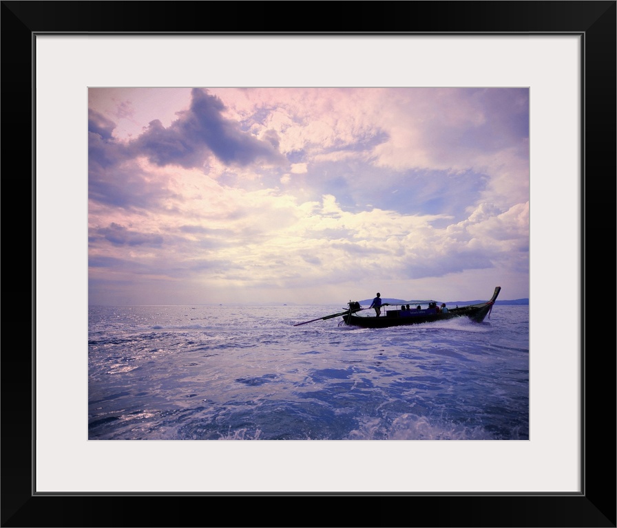 Wooden boat sailing on ocean at sunset, Thailand.