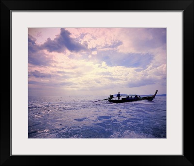 Wooden boat sailing on ocean at sunset, Thailand.