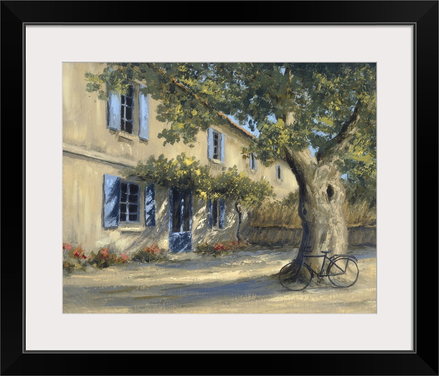 A European country home with a large tree in the front yard with a bicycle.