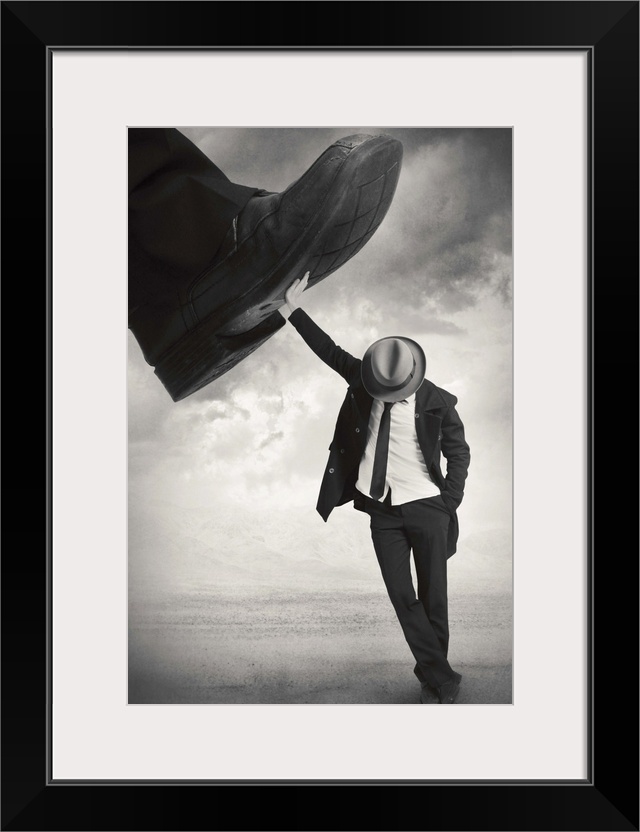 An abstract art photograph of a man wearing a hat and suit, leaning against a giant foot trying to step on him.