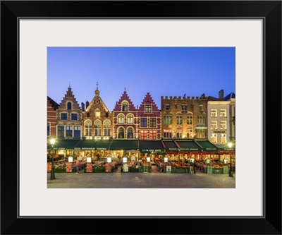 Belgium, Bruges. Medieval guild houses and restaurants on Markt square at dusk