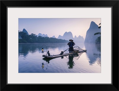 China, Guanxi, Yangshuo. Old chinese fisherman on the Li river, fishing with cormorants