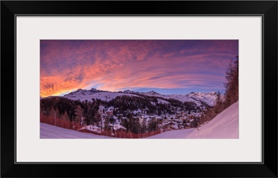 Panorama of the alpine village of Madesimo and snowy ski slopes at sunset