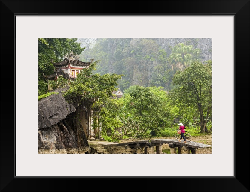 Woman crossing bridge with bicycle to temple, Tam Coc nr Ninh Binh, nr Hanoi, Vietnam