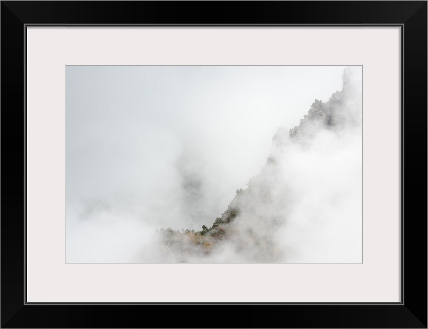 Mountainous valley with seasonally changing foliage shrouded in thick haze.