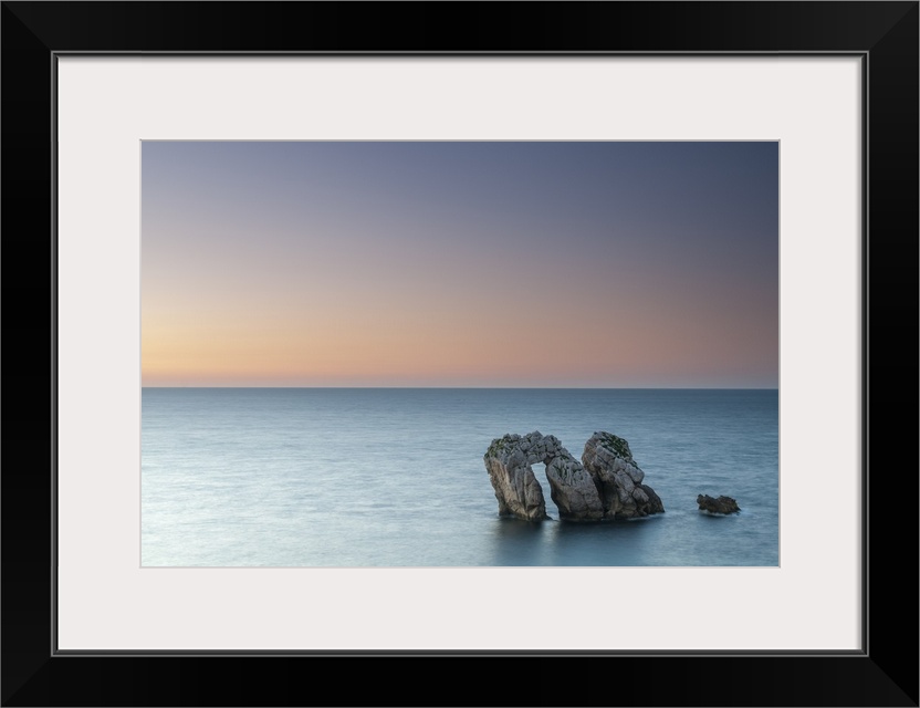 Archway boulders in a blue ocean at sunset.