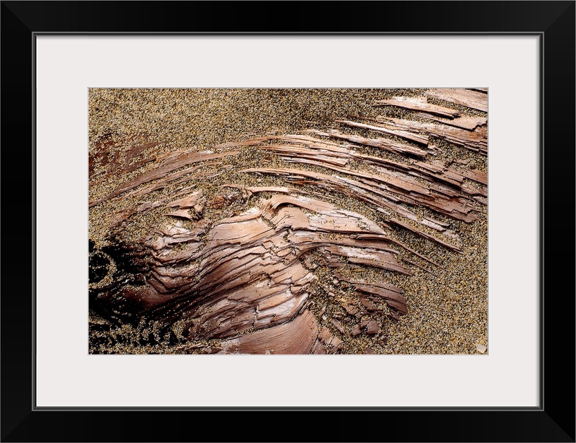 Photograph of dirt covering smooth copper-like rock.