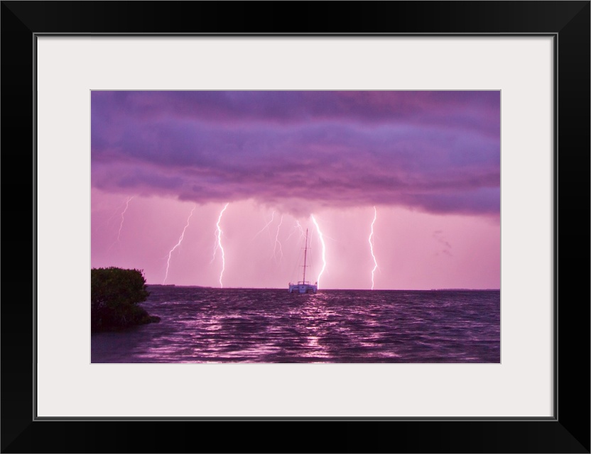 Lightning bolts striking the ocean, and almost hitting a sailboat.