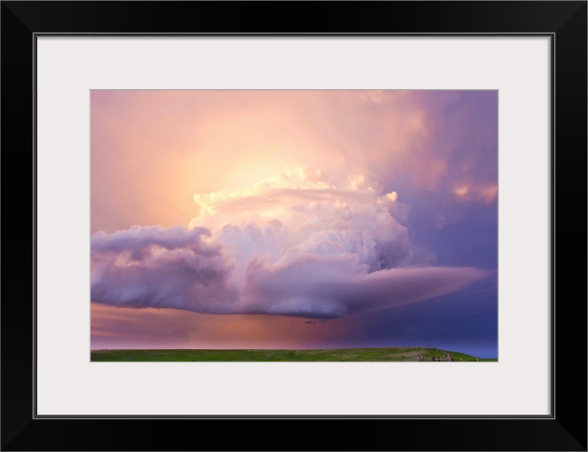 Sunset paints a decaying thunderstorm and the sky a glowing purple and pink.