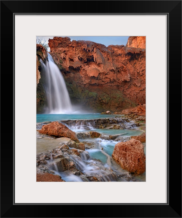 Large photograph showcases water falling down a jagged cliff and splashing into the pool below before moving on down a roc...