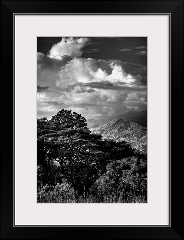 Black and white photograph of dramatic clouds hanging over a mountain peak.