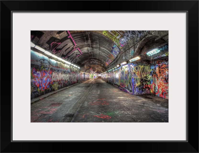 HDR photograph of city tunnel walls covered in graffiti.
