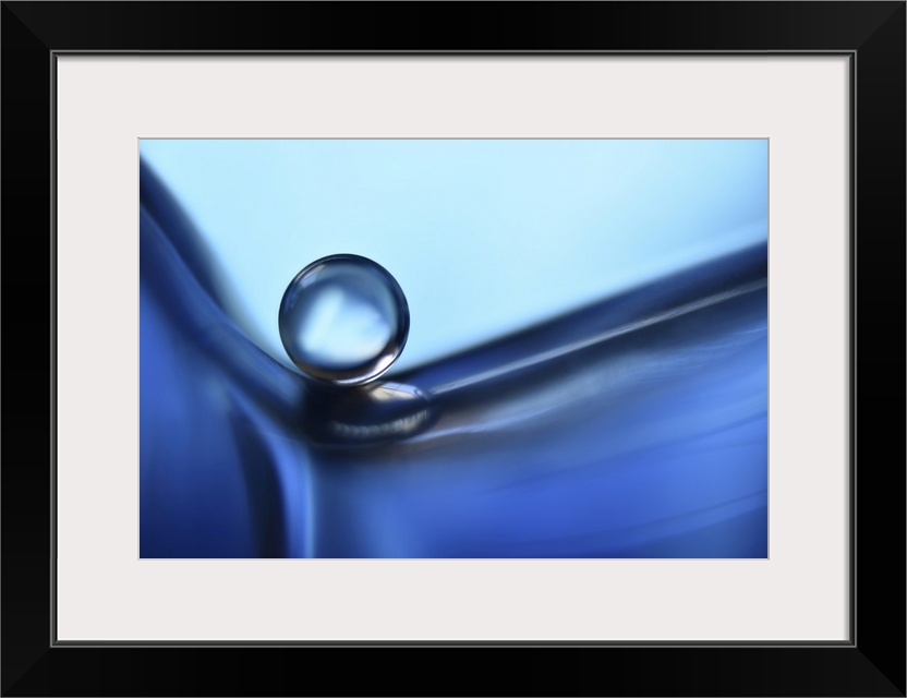 A water pearl laying on a glass perfume bottle.