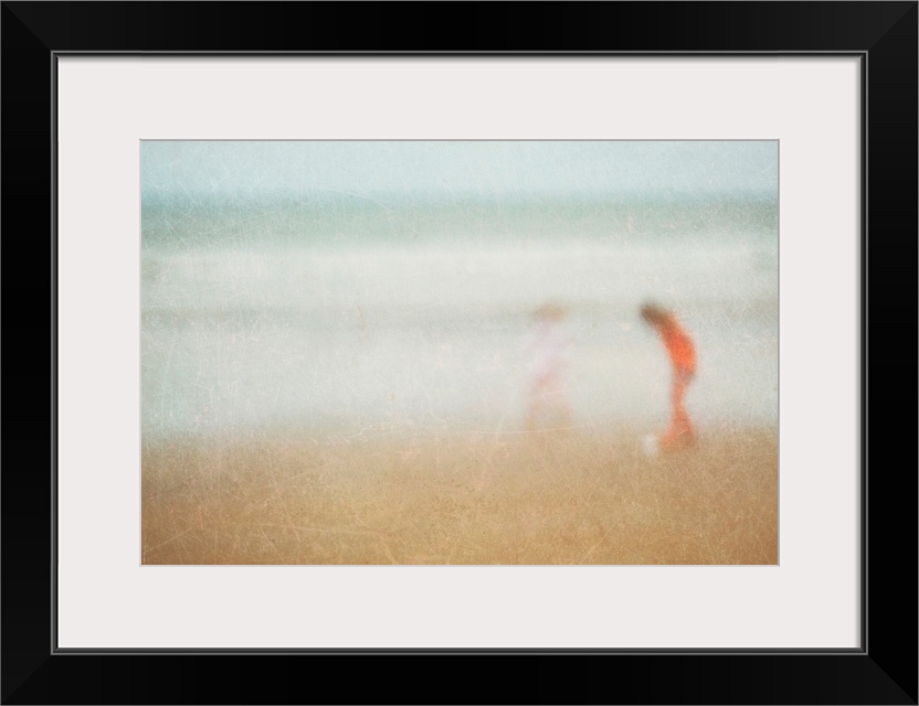 Giant photograph shows two children playing on a sandy beach at the edge of an ocean.  Photographer sets a very soft focus...