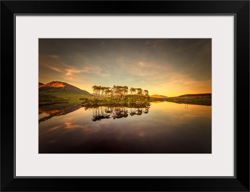 Sunset over a lake with the reflection of a cluster of trees