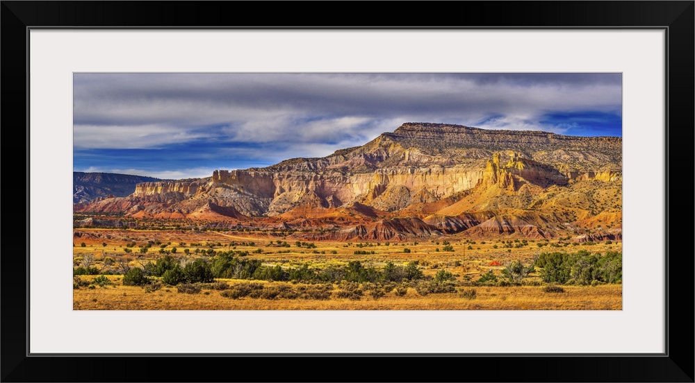 A myriad display of mountainous desert rock formations featuring rusty reds, yellows, browns, grays and whites dotted with...