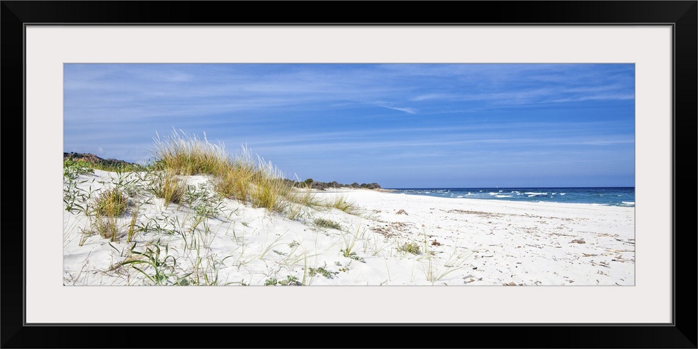 This picture was shot in Sardinia in the summer. A lonely beach with dunes and shrubs with the sea in the distance of a de...