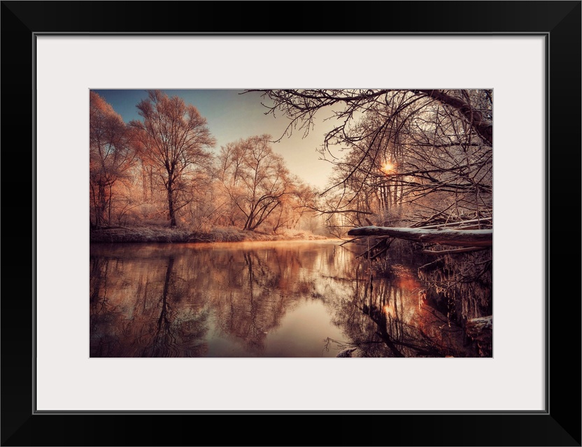 In this landscape photograph morning light reflects off a river in a forest covered with the first frost.