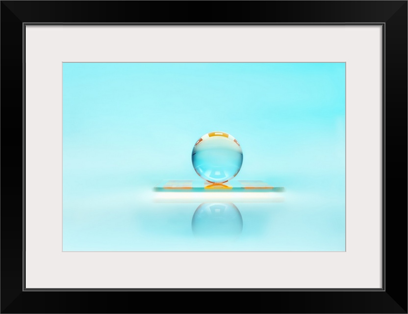 A clear glass sphere resting against a turquoise backdrop.