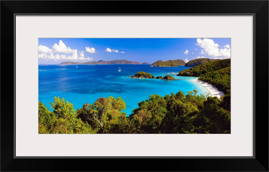 Panoramic photograph of cove with water on left and tree lined beach on right.  There are vegetation covered mountains in ...