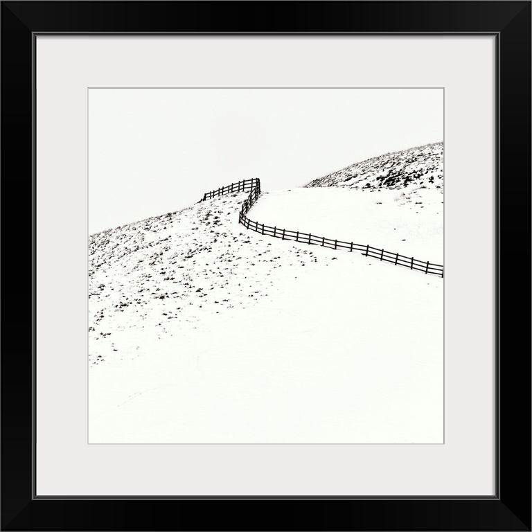 A contemporary minimalist winter landscape showing a curving fence climbing a snow covered hill.