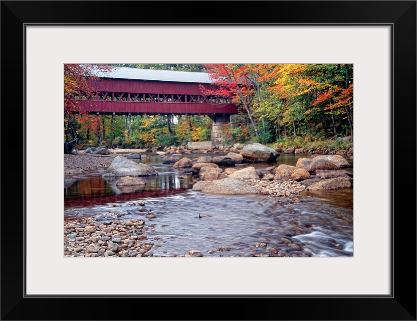 Photograph of the wooden Swift River Bridge located in Conway, New Hampshire that overlooks a river flowing through rocks ...