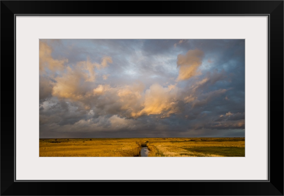 Photograph of a beautiful skyscape in Norfolk, England, with a stream in the center moving towards the horizon line and li...