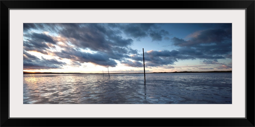 A Panoramic Sunrise over the Pilgrims Causeway at Lindisfarne on Holy Island, Northumberland, UK with fluffy clouds and go...